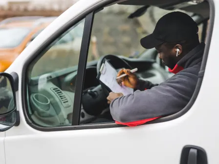 Deliveryman looking at paperwork showing mailable, shippable, and deliverable addresses