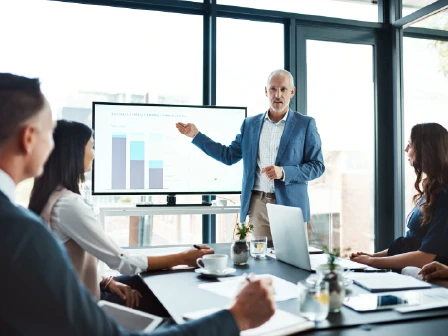 Man presenting graph to a team of three individuals